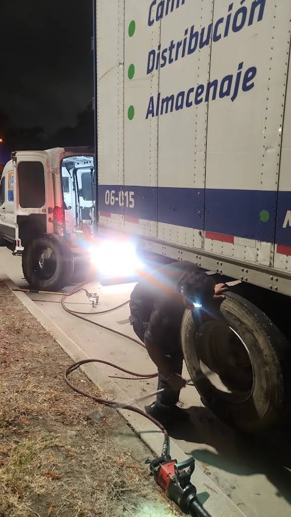 Technician working on a trailer wheel at night